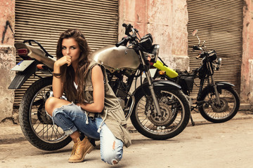 Naklejka na ściany i meble Woman is posing beside old motorcycles