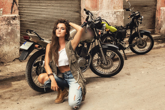 Woman is posing beside old motorcycles - Powered by Adobe