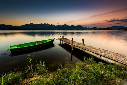 Rowing boat at dock with mountain lake, Allgau Alps at back, blue hour, Hopfensee, Hopfen am See, Ostallgau, Bavaria, Germany, Europe