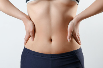 Fototapeta na wymiar close-up photo. a slender girl in sports leggings and a topic shows a tight figure and a tummy, holds her hands on the sides of the waist on white background