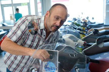 handsome manexamining motorbikes in a motorbike salon