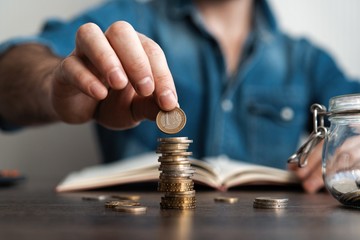 Business man putting a coin on coins stack saving bank and account for his money all in finance accounting concept.