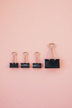 Black Paper Clips Against Pink Background