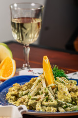 Fresh salad with chicken, orange, apple and green curry sauce. Served with white wine and cheese on the blue plate. Wooden background. horizontal view