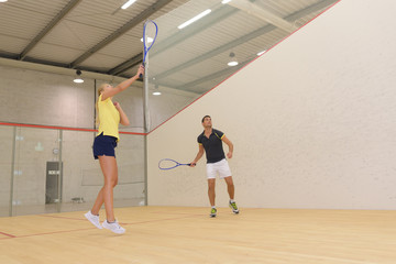 couple with squash rackets playing indoor