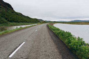 The road between the mountains and the hills. Asphalt road in Iceland. The road is in the field.