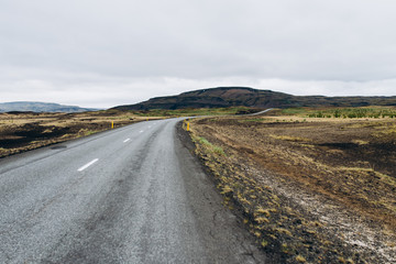The road between the mountains and the hills. Asphalt road in Iceland. The road is in the field.