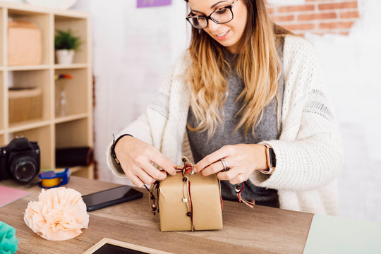 Young woman wrapping a gift in her studio