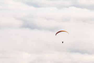 Paraglider flies on the background of clouds on a sunny day. copy space