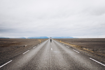 Asphalt road in the field. the man goes in the middle of the asphalt road. The guy goes along an asphalt road.