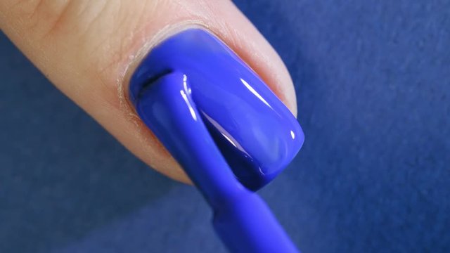 Beautiful manicure process. Nail polish being applied to nail, polish is a blue color.