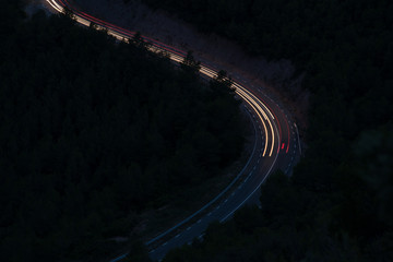 curve of a road in the forest painted by cars