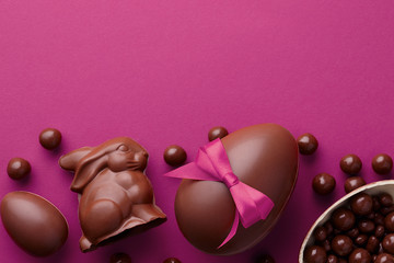 Easter composition with chocolate eggs and bunny on purple background, holiday concept