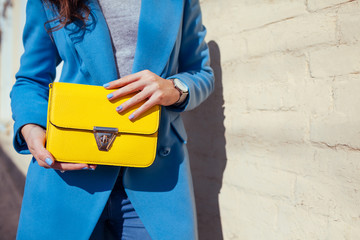 Young woman holding stylish handbag and wearing trendy blue coat. Spring female clothes and accessories. Fashion