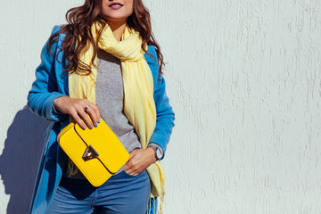 Young woman holding stylish handbag and wearing trendy blue coat. Spring female clothes and accessories. Fashion - obrazy, fototapety, plakaty