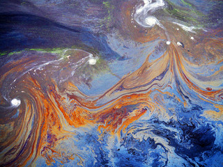Rainbow colored oil floating on water. Gasoline stains. Colored texture, natural background. Ecological problem. Oil spill. Water pollution