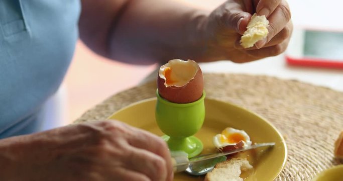 Person eating eating oeuf a la coque in the morning for breakfast