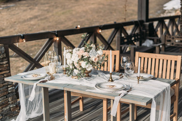 Luxury decorated table and wedding cake for a romantic date. Wedding details: tablecloth, candles, plates, glasses, near a mountain river on background. Wedding, calligraphy vintage, perfect view on m