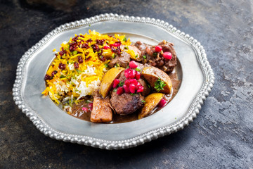 Traditional Iranian khoresh beh stew with chunks of lamb, quinces and saffron rice as a closeup on a pewter plate