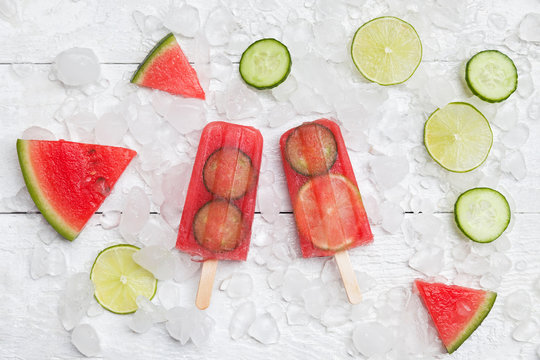 Homemade watermelon cucumber ice lollies on white ground