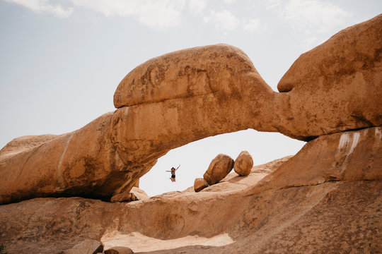 Namibia, Spitzkoppe, woman jumping at rock formation