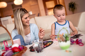 Mother and her son painting colorful Easter eggs