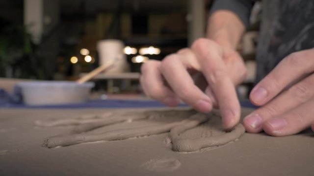 ceramist lays out a pattern on the future vase for flowers, dolly shot