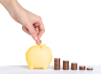 Woman putting coin into gold piggy bank on white background. Space for text