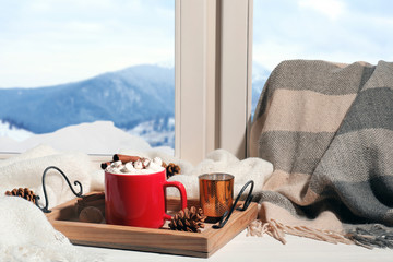 Composition with cup of hot winter drink on tray near window