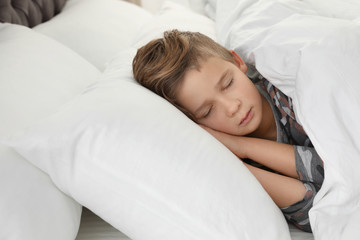 Cute tired boy sleeping in comfortable bed