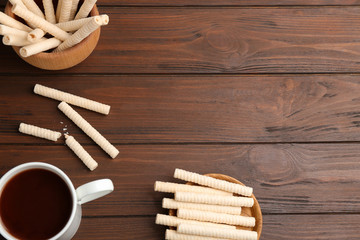 Flat lay composition with wafer rolls and cup of cocoa on wooden background, space for text
