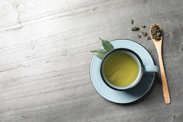 Cup of Tie Guan Yin oolong and spoon with tea leaves on table, top view. Space for text