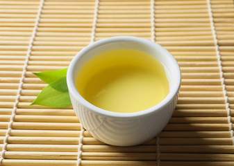 Cup of freshly brewed oolong tea on bamboo mat