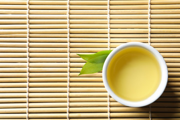 Cup of freshly brewed oolong tea on bamboo mat, top view with space for text - obrazy, fototapety, plakaty