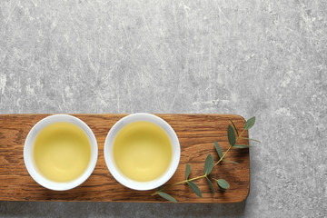 Obraz na płótnie Canvas Stand with cups of freshly brewed oolong tea on grey background, top view with space for text