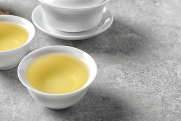 Fototapeta na wymiar Cups of freshly brewed oolong tea on grey table. Space for text