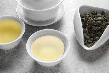 Obraz na płótnie Canvas Cups of Tie Guan Yin oolong and chahe with tea leaves on grey table