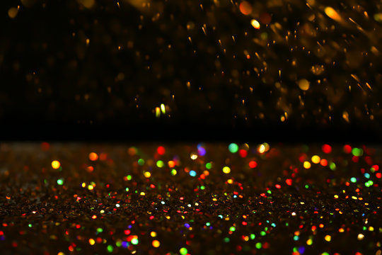 Many golden paillettes against black background. Space for text