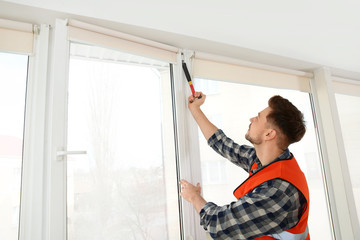 Fototapeta na wymiar Construction worker installing plastic window in house