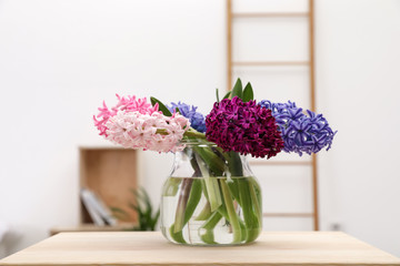 Beautiful hyacinths in glass vase on table indoors. Spring flowers