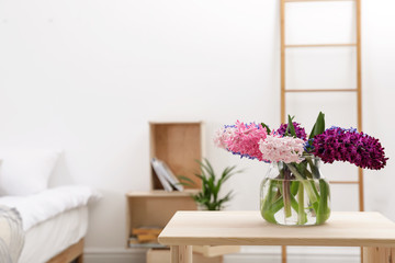 Beautiful hyacinths in glass vase on table indoors, space for text. Spring flowers
