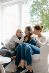 Happy mother with two teenage girls on couch at home