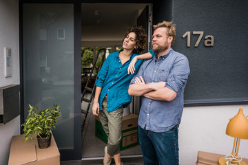 Couple standing at house entrance with cardboard boxes