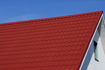 red tiles on the roof of the attic with a window against the blue sky