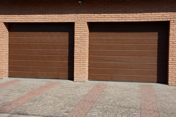 facade of a brown brick garage with two gates in the street