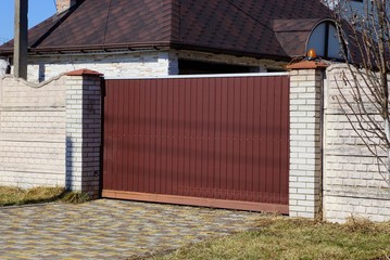 brown metal gate and gray brick fence on a city street