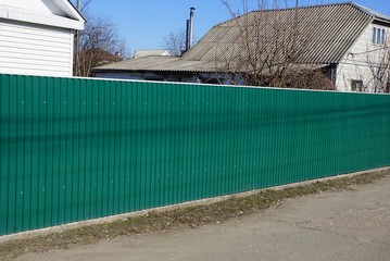 long metal green fence on the street by the road