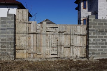 gray old wooden gate and brick fence on rural street