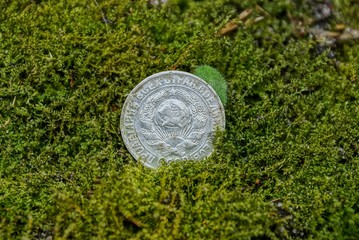 old silver soviet coin with the coat of arms lies on the green moss