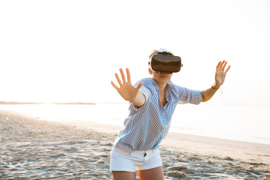 Thailand, woman using virtual reality glasses on the beach in the morning light